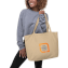 Ein weibliches Modell hält eine Tragetasche aus Canvas mit einem beispielhaften Logodesign
